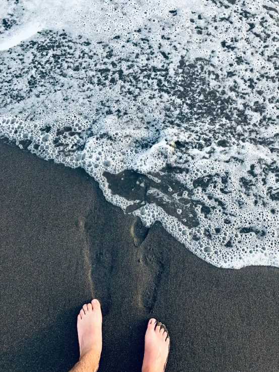 feet on the beach next to the water and sand