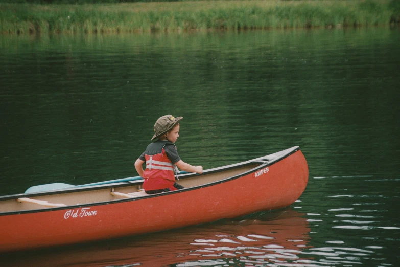 a child wearing red shorts is on the water in a canoe