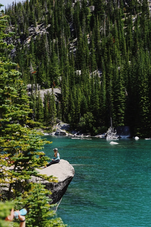 an individual sitting on a rock in the water