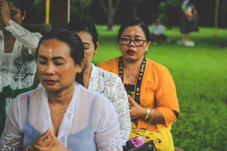 a group of women that are sitting in the grass