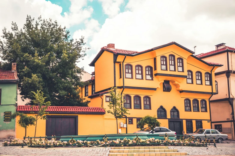 yellow colored house with three stories near green trees