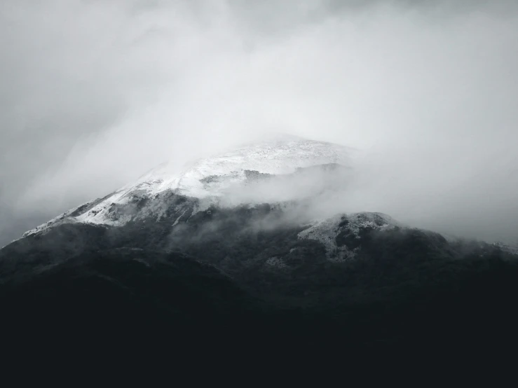 the silhouette of a snow - covered mountain on a gloomy day