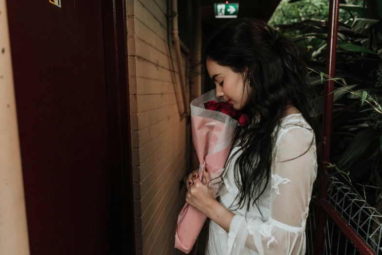 woman holding a vase with flowers in it standing outside