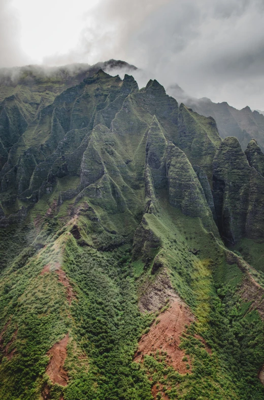 many large, green mountains are on a cloudy day