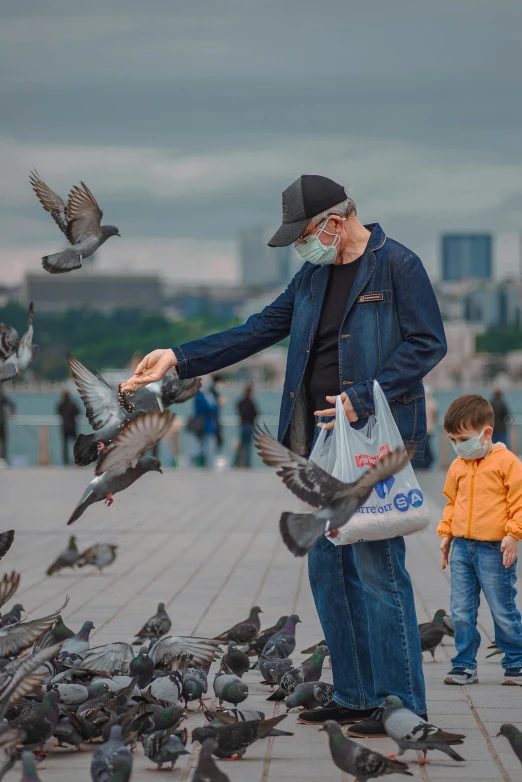 a man feeding birds in front of a city