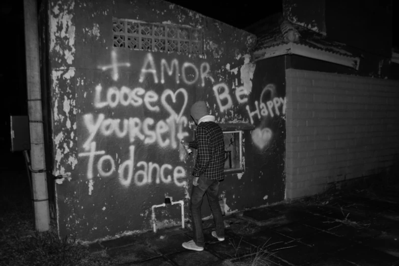 a man standing in front of a wall with graffiti