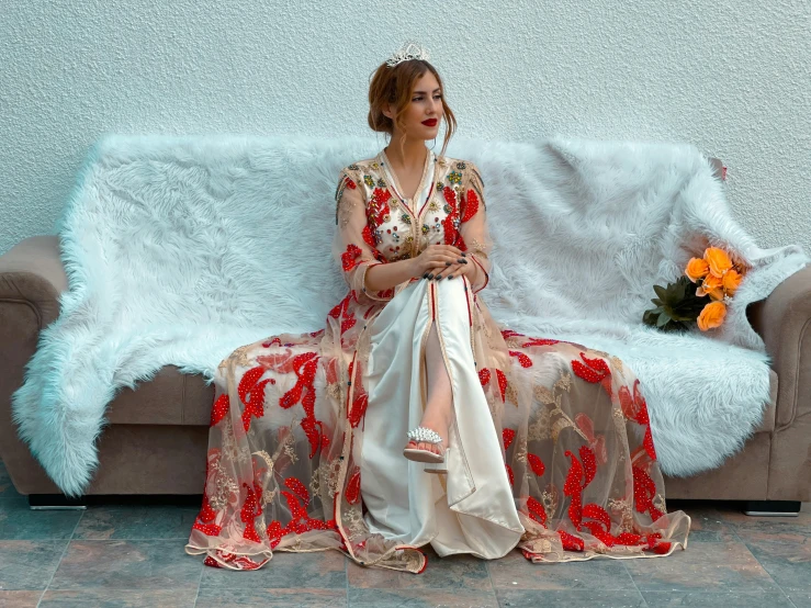 a woman wearing red and white sitting on a grey couch