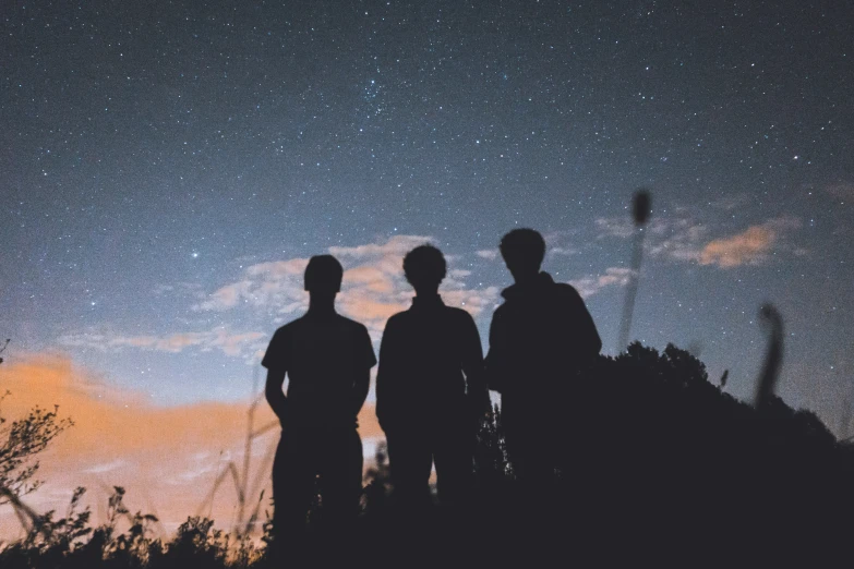 two men standing together near a forest at night