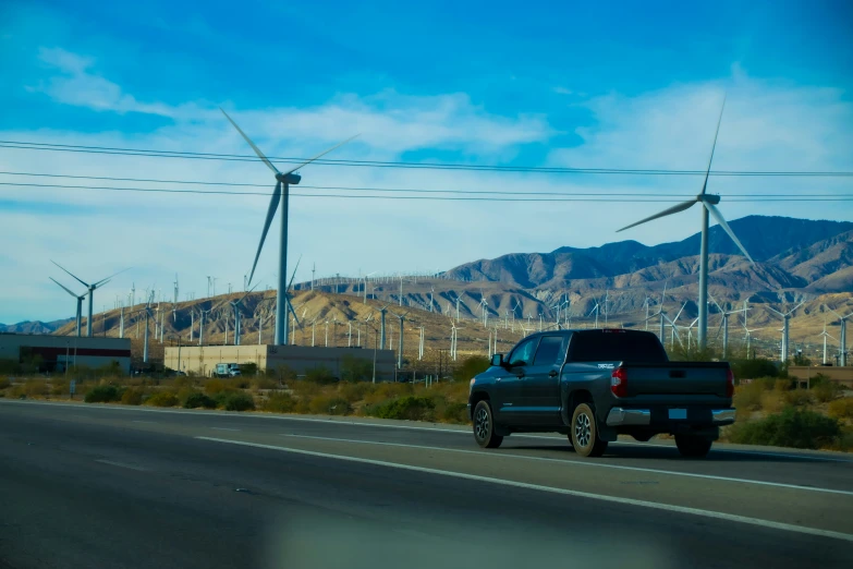 there is a black truck driving next to the wind