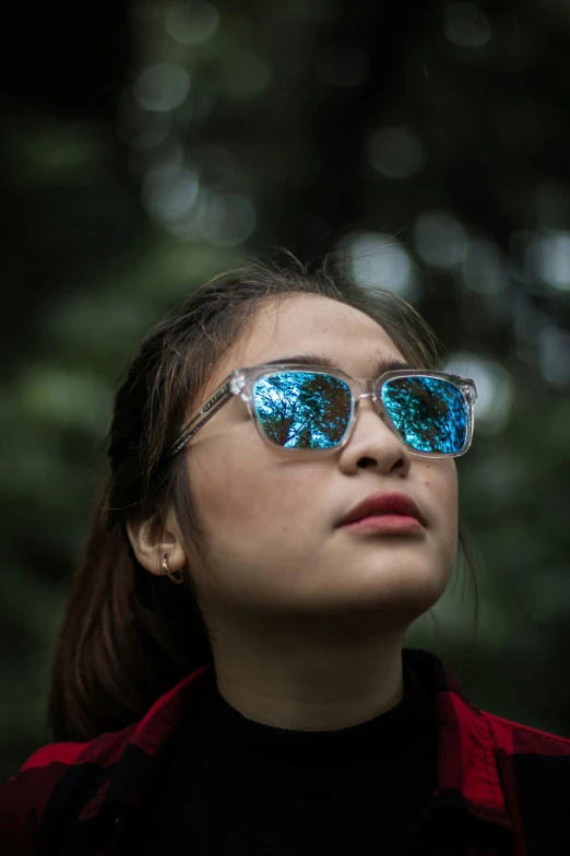 a girl in the foreground wearing pair of blue tinted sunglasses