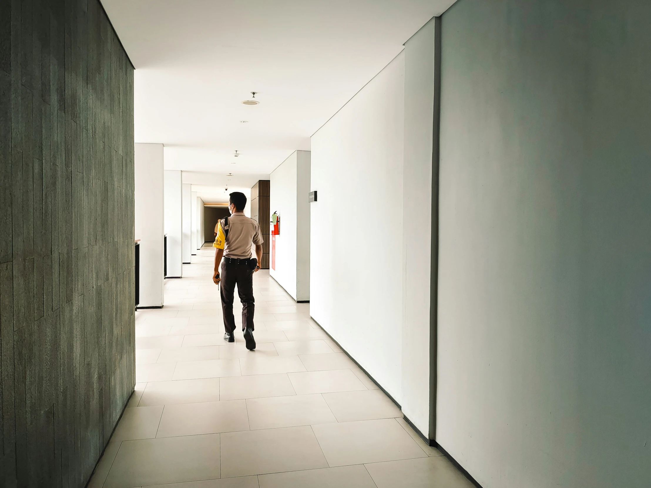 a long hallway with a guy walking in the background