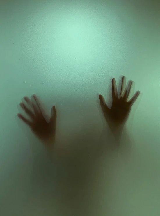 two hands are silhouetted in the fog on a wall