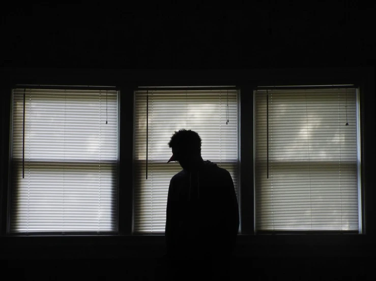 silhouette of a man in front of three windows