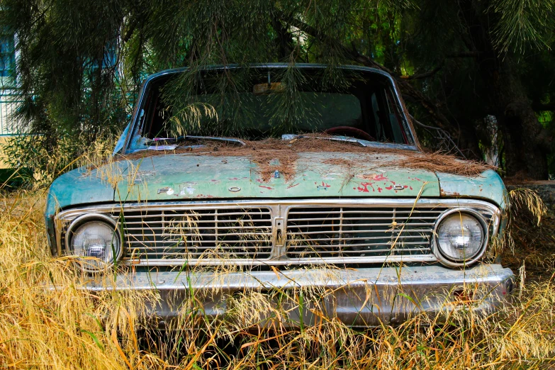 an old rusty and stained car sitting in a field