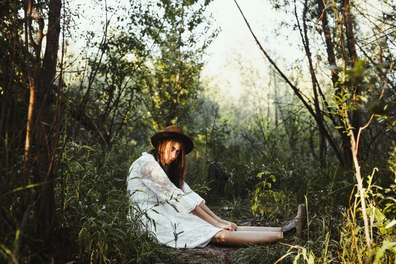 a bearded man wearing a hat is sitting in the woods