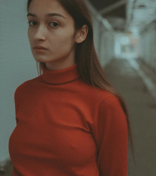 a woman with long hair wearing an orange turtle neck
