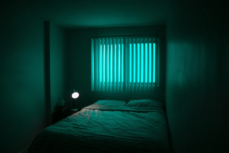 a dimly lit room with a bed with a green light on