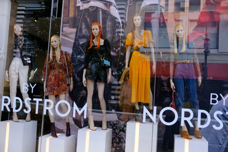 several mannequins of women are behind glass