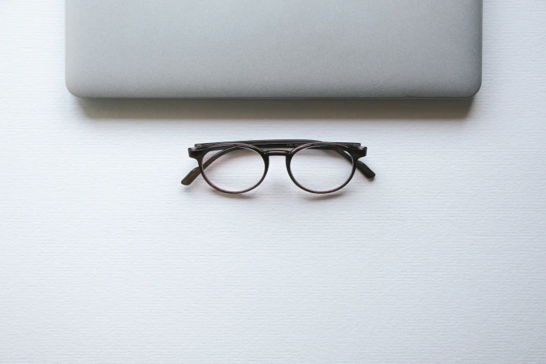 a pair of glasses and computer on a white surface