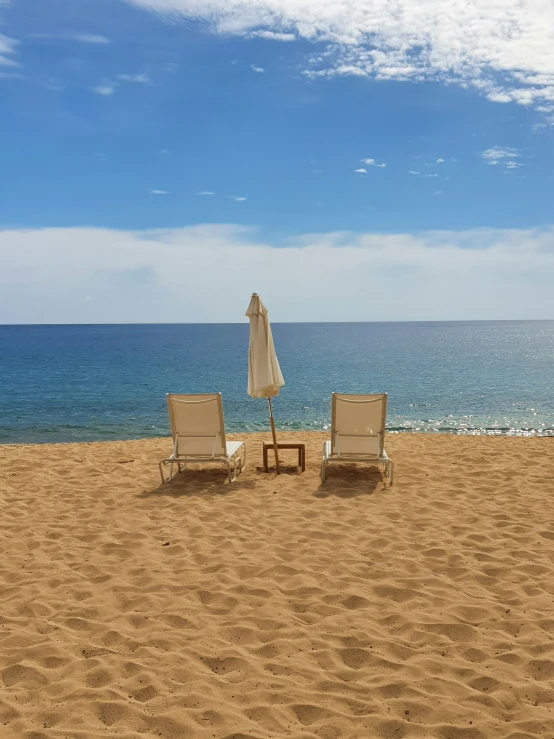 two empty chairs are sitting on the beach