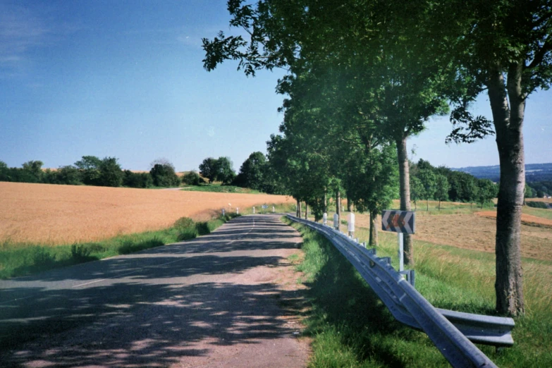 a road in a country side with a farm field behind it