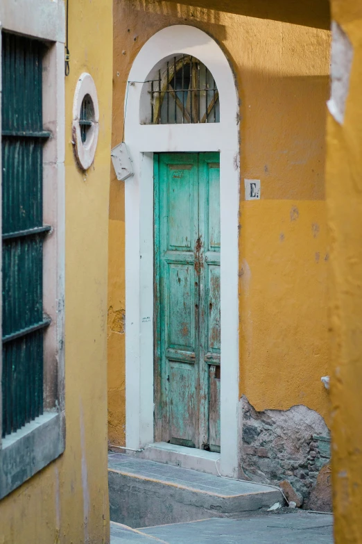 a green door sitting between two yellow buildings