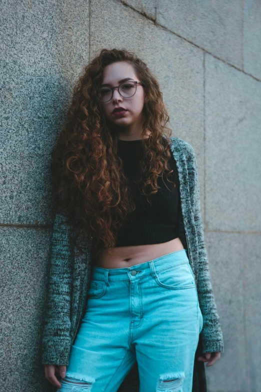 a woman with long hair standing against a building