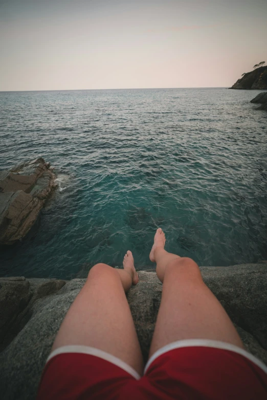 a pair of legs standing on a wall above water