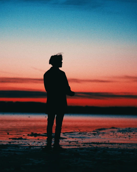 a person is standing on the beach at sunset