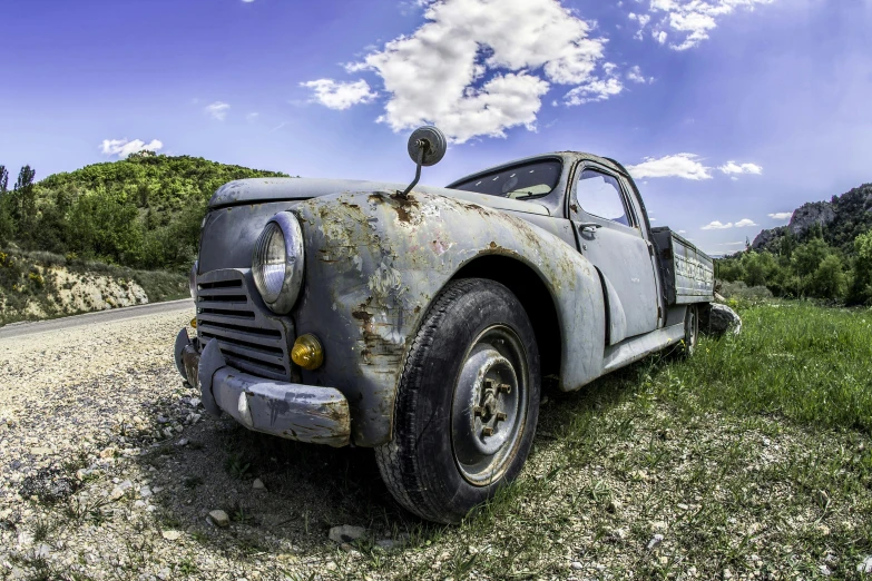 an old rusty, broken down truck sitting on the side of a road