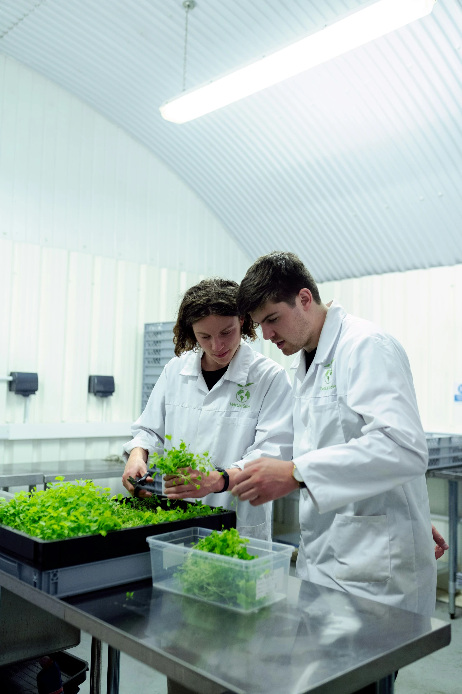two men in lab coats with small green plants