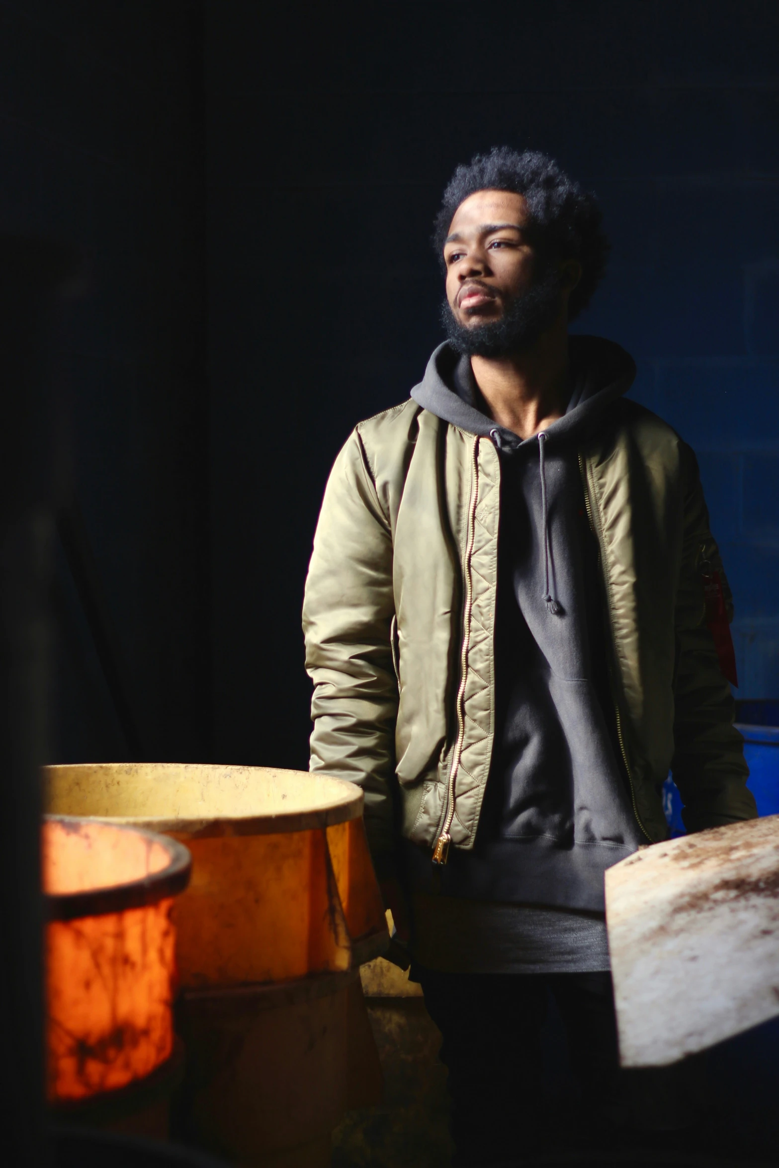 a man with black hair stands in front of drums