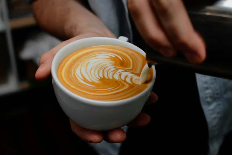 the person is pouring the liquid into the cup