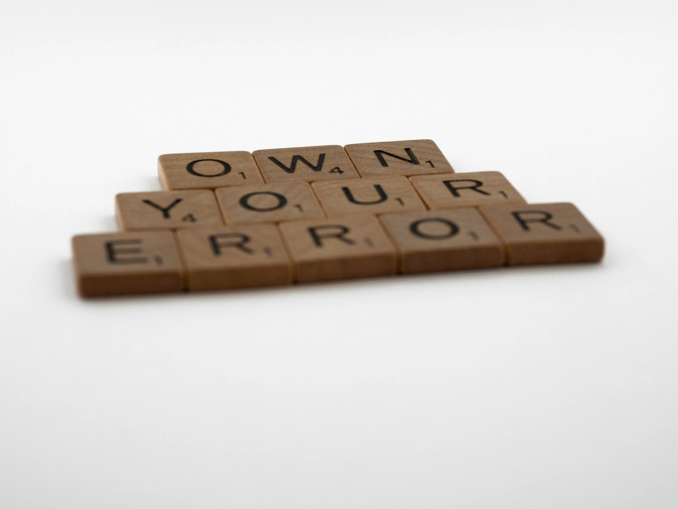 four pieces of scrabble spelling words on a white surface