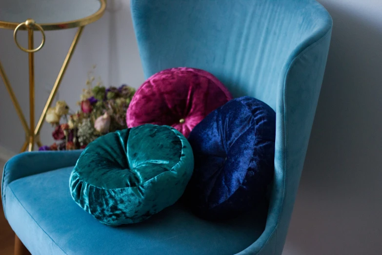 a blue chair has three round pillows sitting on top of it