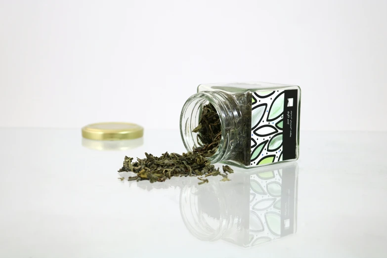 a small container of marijuana sits beside a tin of pepper