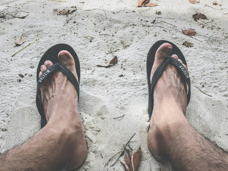 person with flip flops and sandals at the beach