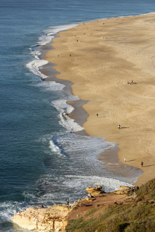 some people walking along the side of a hill by a body of water