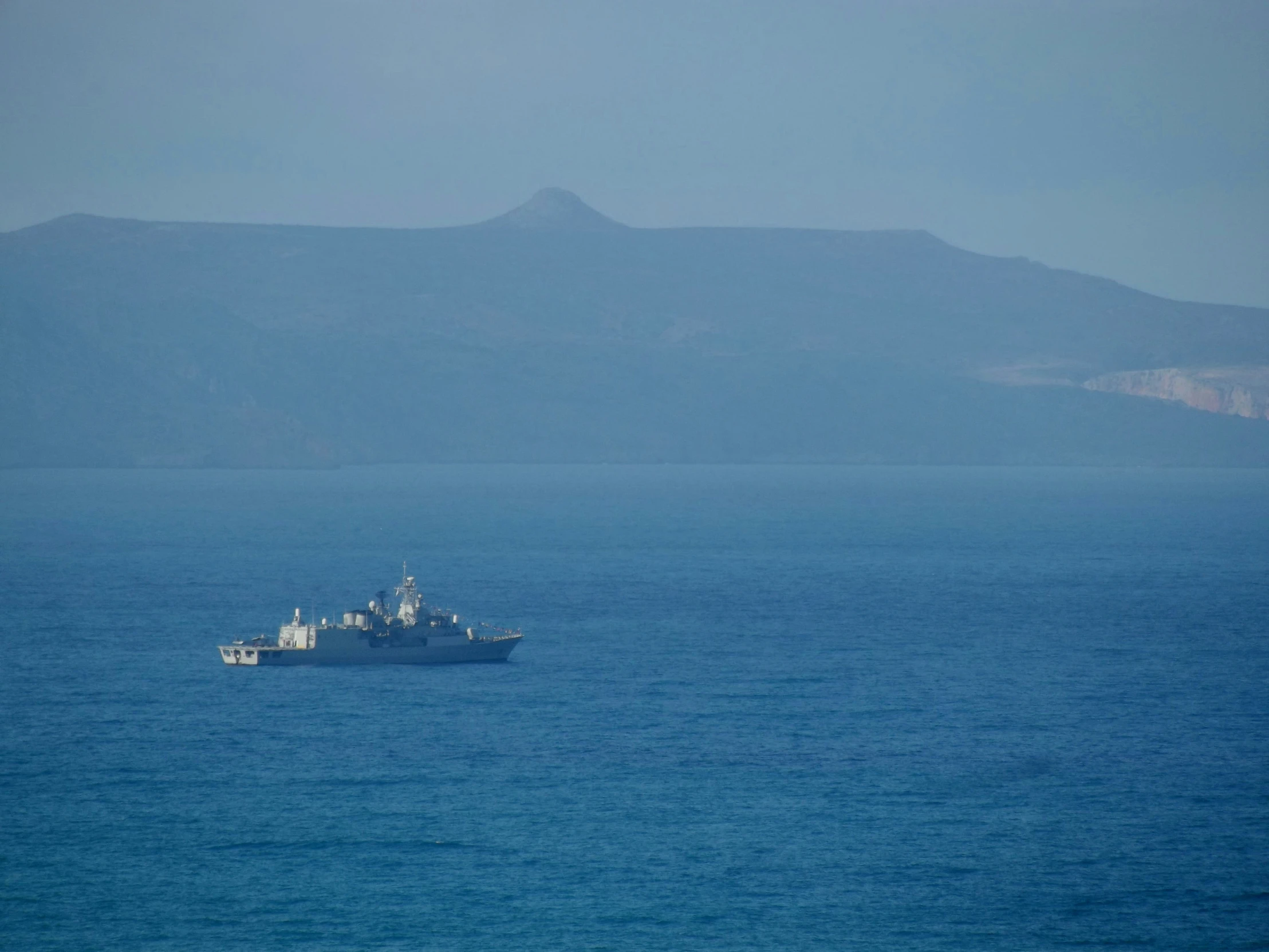 a ship is out in the ocean, in front of mountains