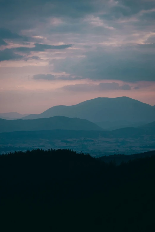 silhouette of mountain range against dusk sky with clouds