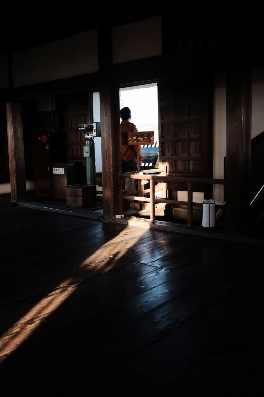 person in dark room with wood paneling and open door