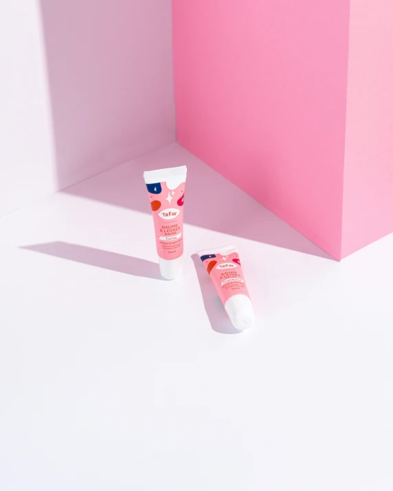 two empty tube of sunscreen against pink wall