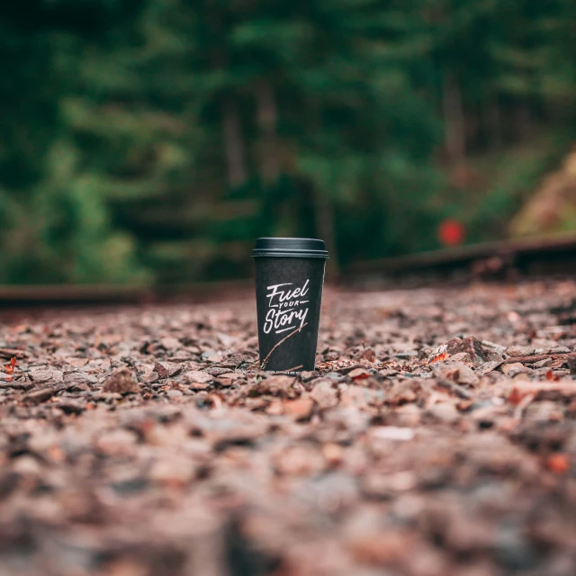 there is a black coffee cup that is sitting on the gravel