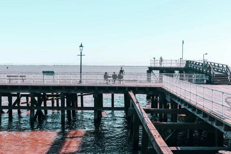 people stand on a wooden dock near the ocean