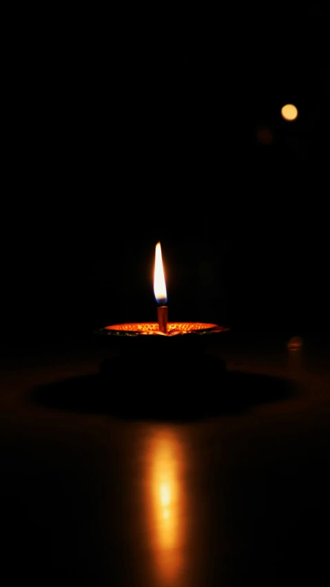 a lit candle in the dark on the table