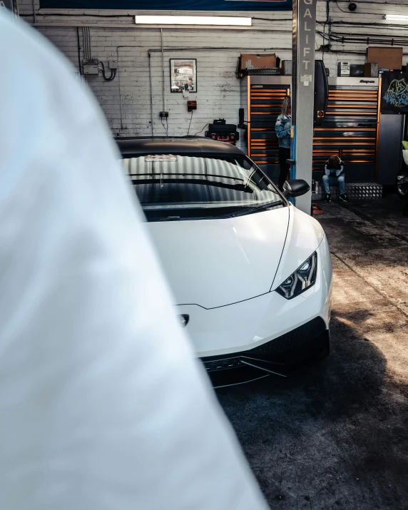 a white lamb car in a garage parked next to a person