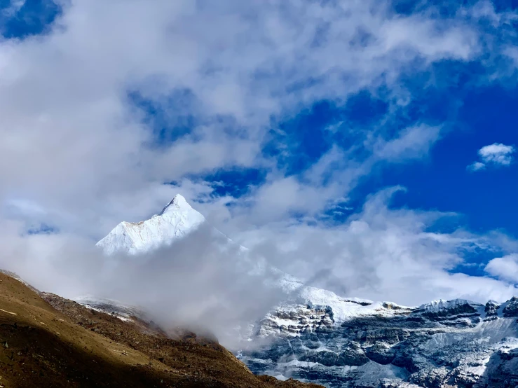 the clouds drift down onto the top of a snowy mountain