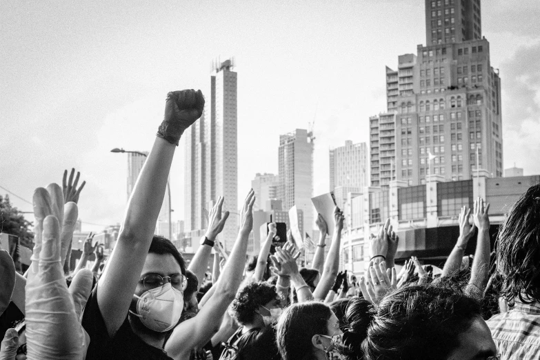 many people raising their hands and masks in the air