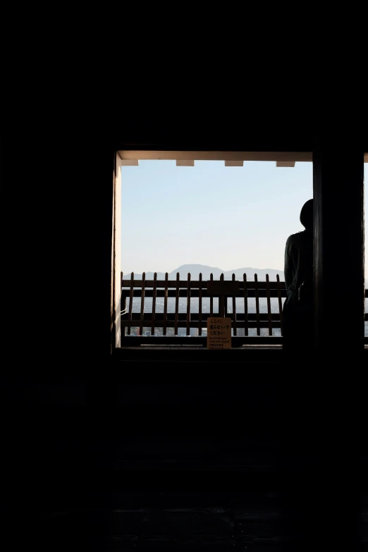 silhouette of a person sitting on a bench looking out to the water