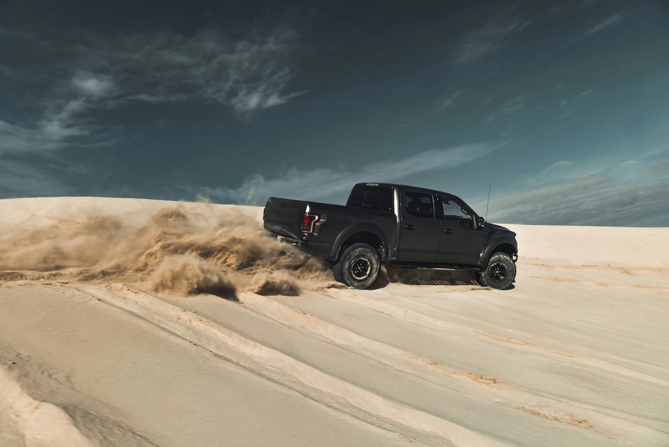 the truck is driving through a sandy field